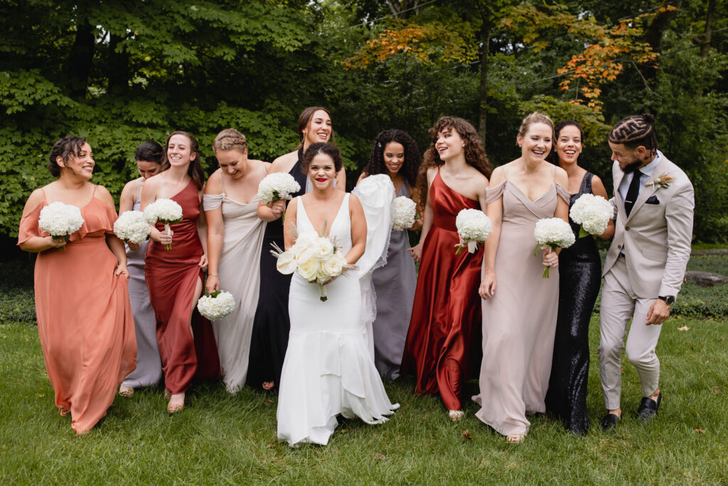 bridesmaids in mixed color dresses walk outside with white bouquets