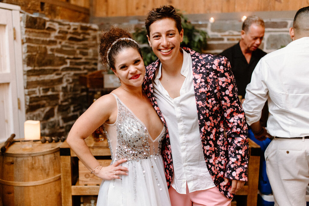brides in a sparkly white dress the other in a white shirt and pink floral suit jacket
