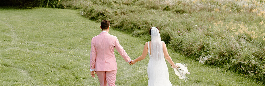 brides walk hand in hand along a field and landscape views upstate