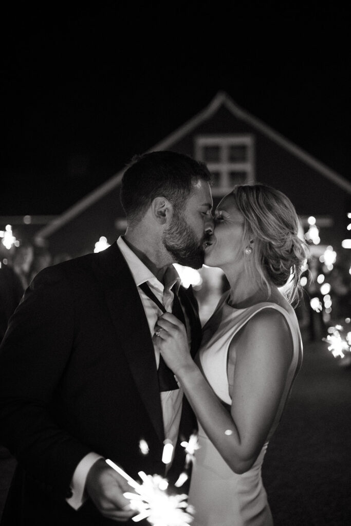 bride and groom kiss in front of sparkler exit from barn wedding reception venue in Upstate New York 
