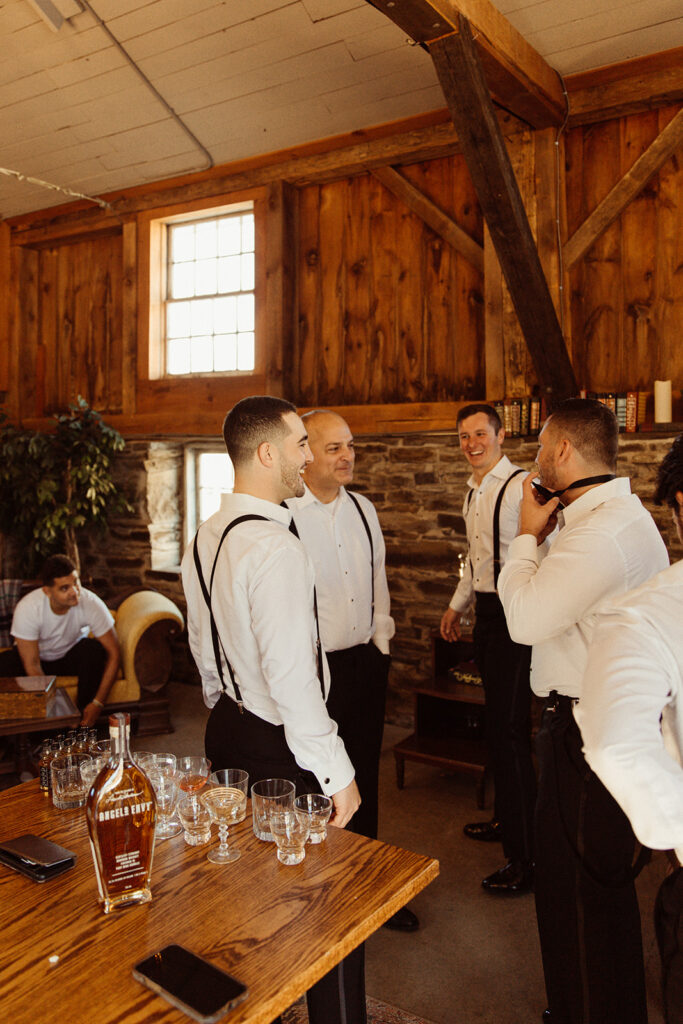 groomsmen getting ready in white stone barn for a fall wedding

