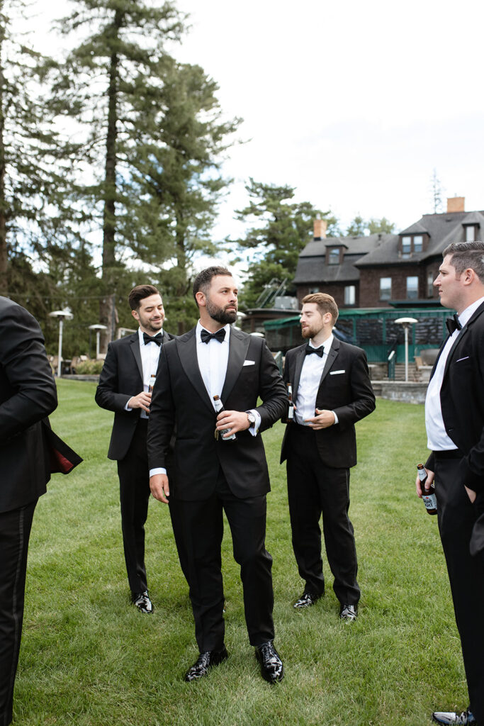 groom and groomsmen outside in Upstate New York wearing classic black tuxedos 