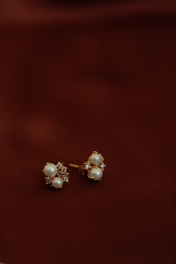 pearl and diamond cluster studs on burgundy fabric