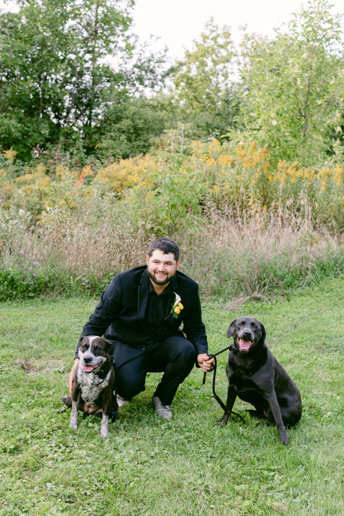 groom outside of dog friendly wedding venue with two dogs