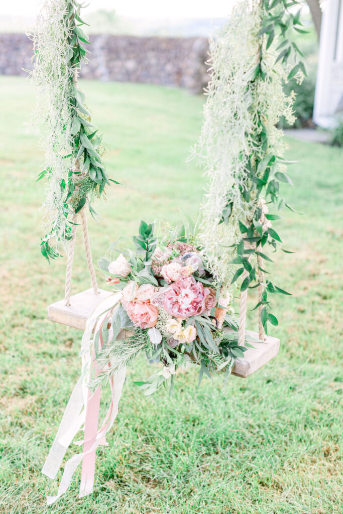 bridal bouquet sits on a tree swing covered in vines 