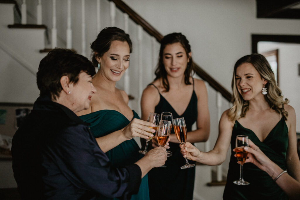 bridesmaids in hunter green dresses toast with sparkling rose getting ready
