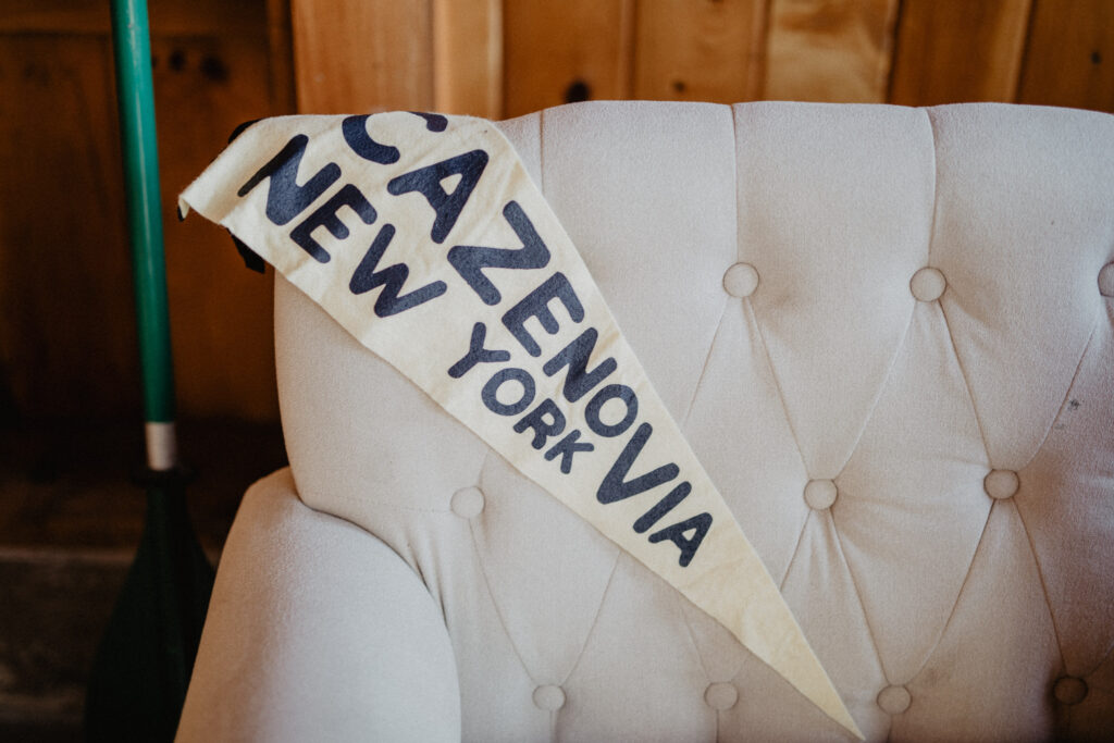 cream and black pennant reads "Cazenovia, New York" drapes on a tufted linen settee 