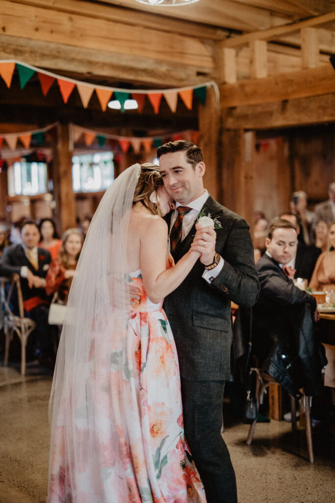 couples first dance in a barn with colorful bunting