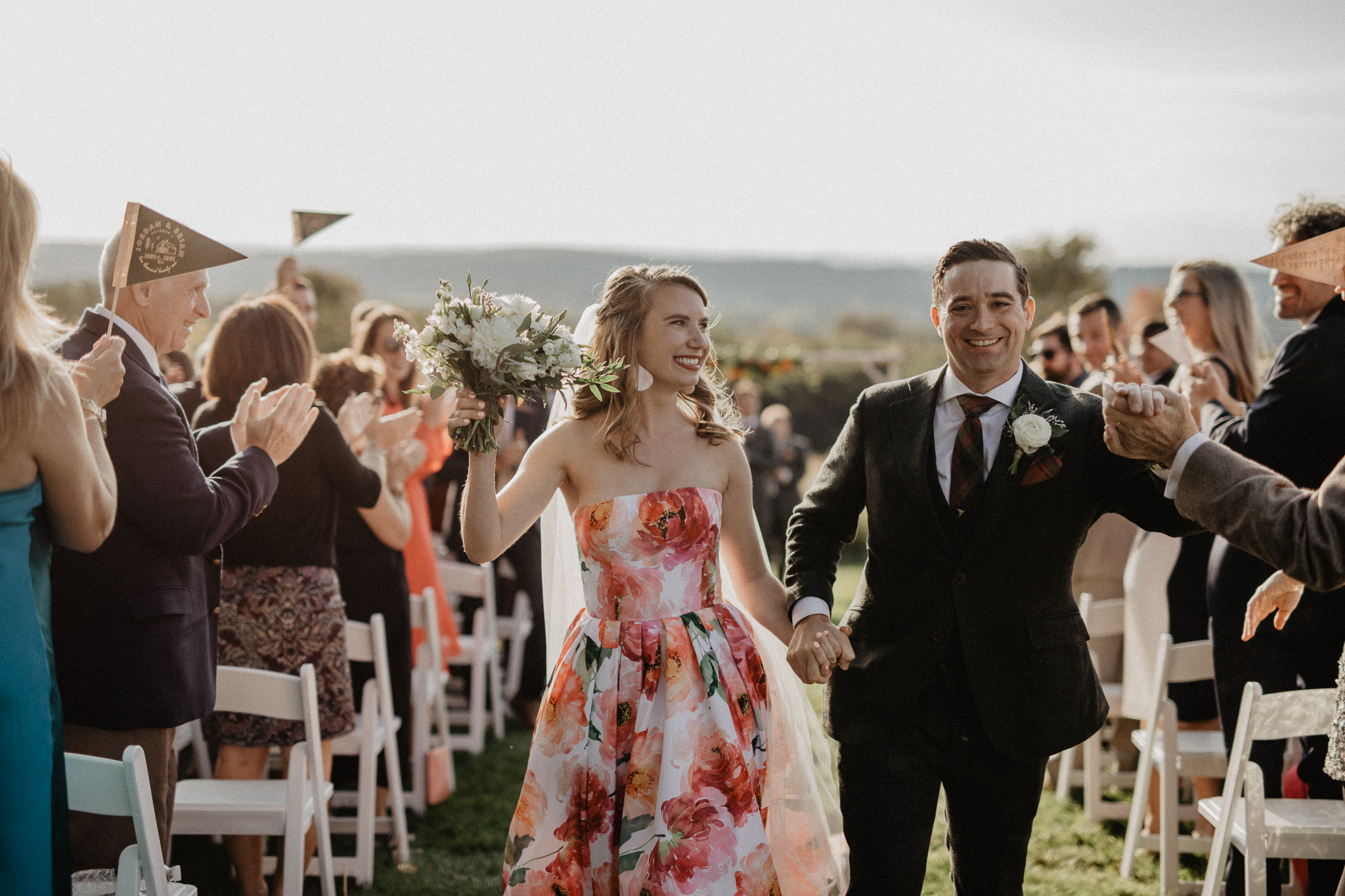 couple exiting outdoor wedding ceremony with bride in colorful wedding dress
