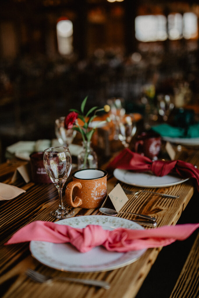 table setting with vintage china and camping mugs for a summer camp wedding reception in upstate new york 