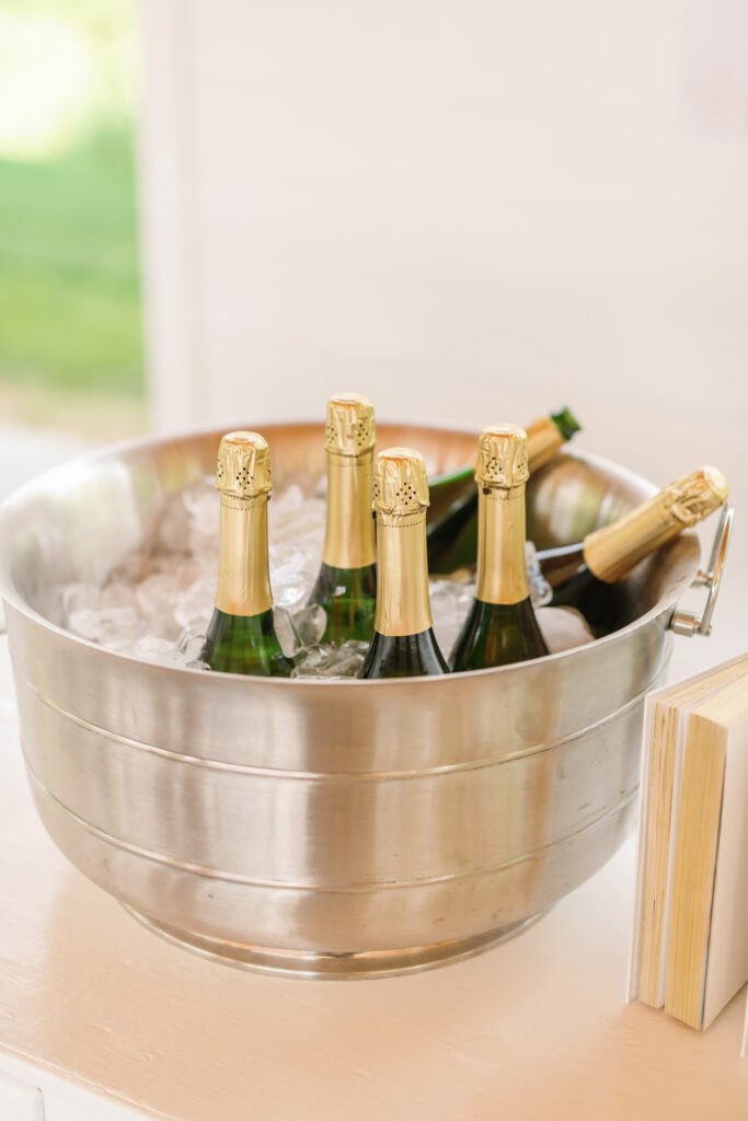 large silver champagne bucket filled with ice and bottles on white bar
