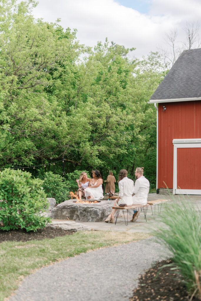 guests around a stone fire pit at event venue in upstate new york
