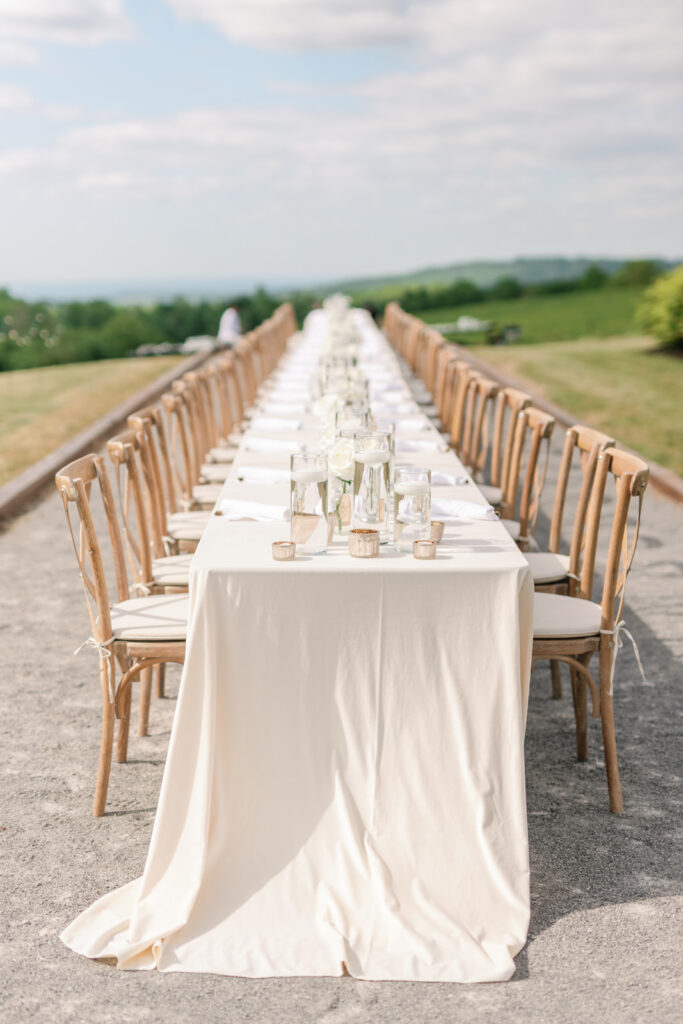 long table outside with white velvet linens and candles